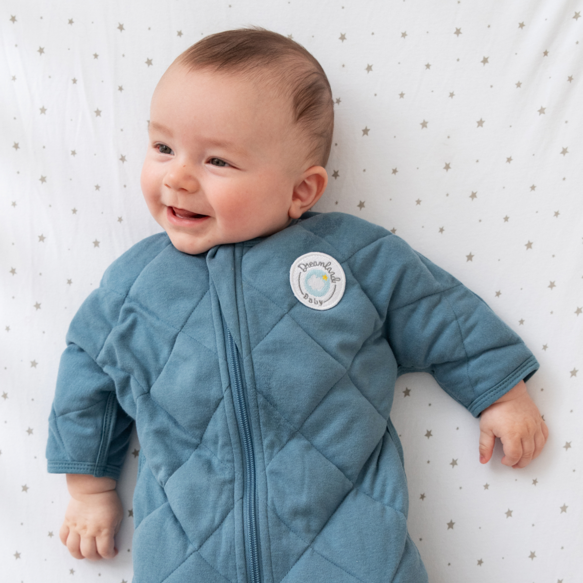 Blue quilted baby sleep sack with a brand logo on a white background