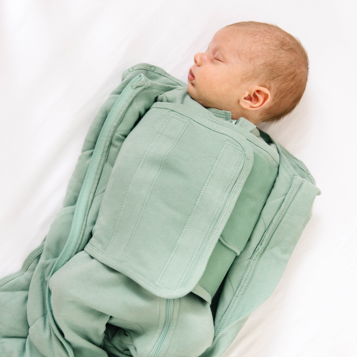 Green quilted baby sleeping bag on a white background