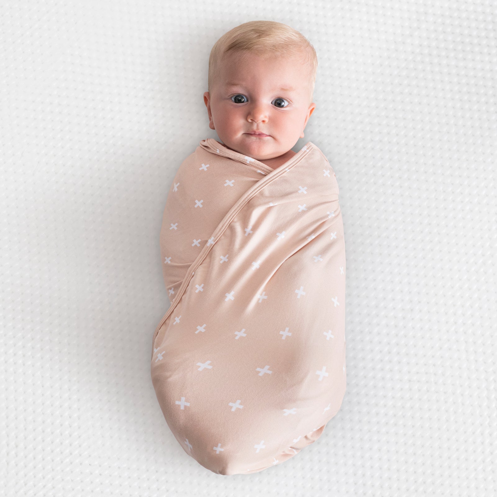 A mocha swaddle blanket with criss cross laid out flat.