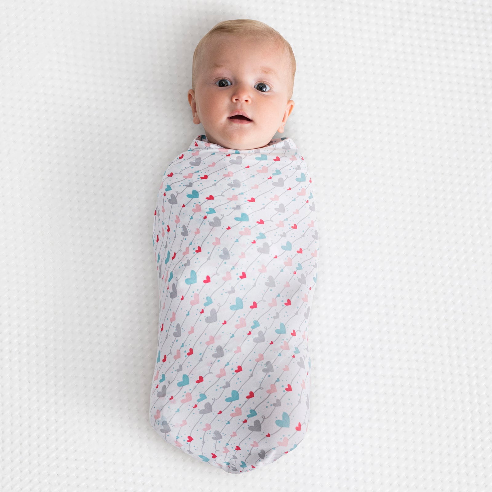 White baby blanket with colorful heart pattern on a white background