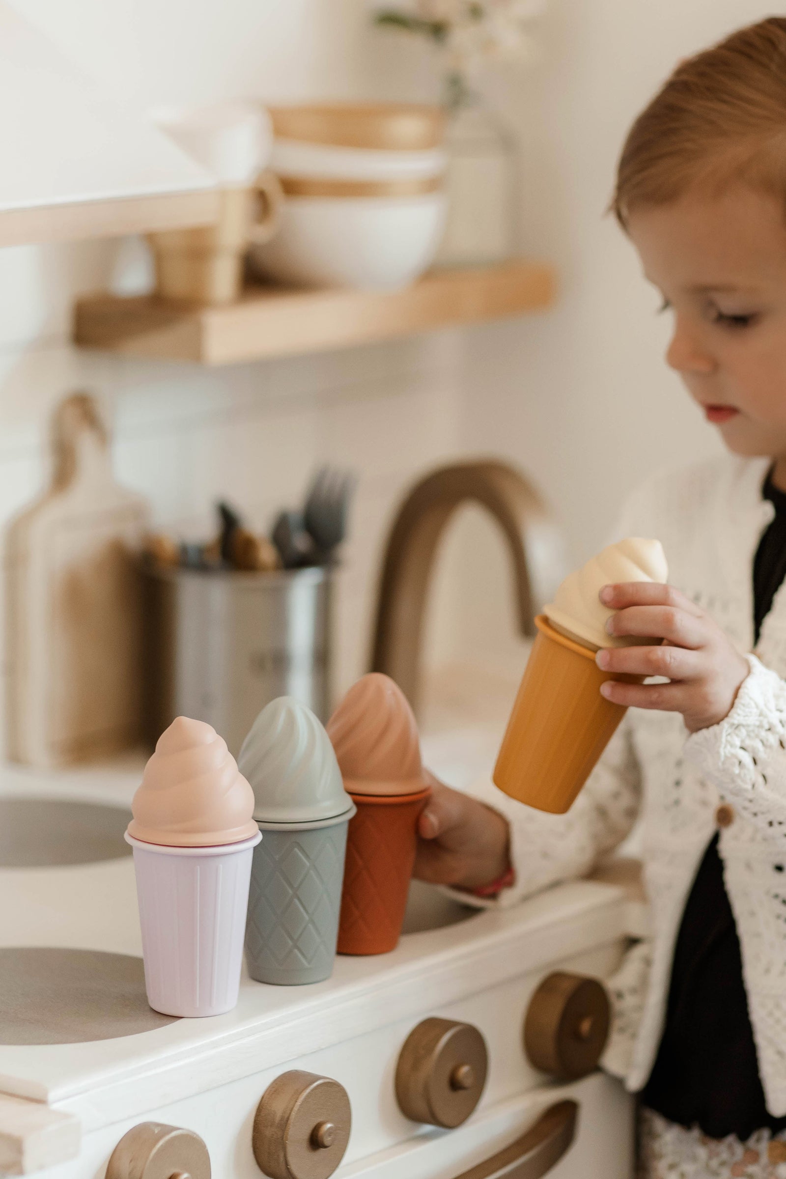 Four ice cream cones with different colored tops on a white background