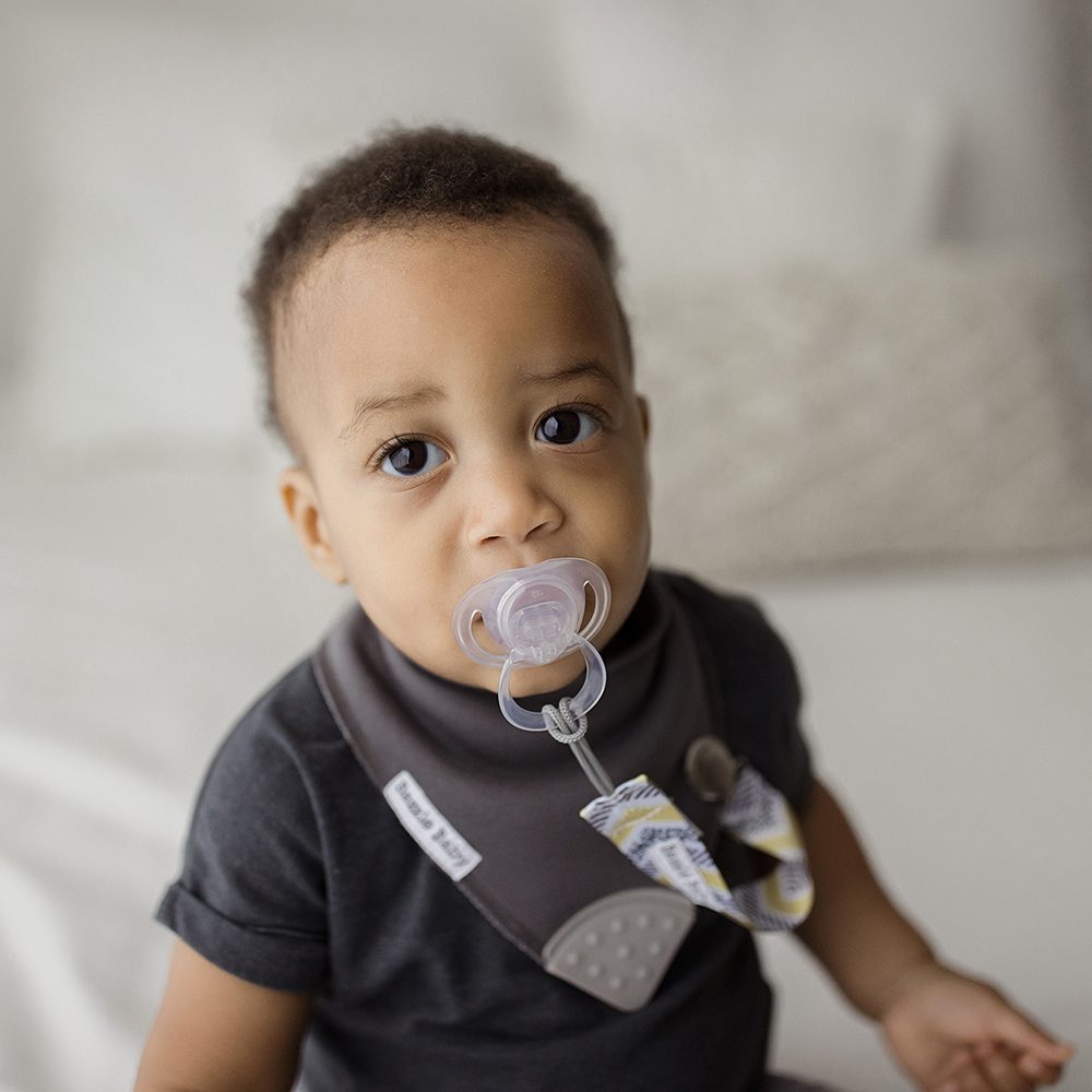 Bazzle Baby Paci Loop attaches pacifiers to bibs and onesies. Grey and white triangles.